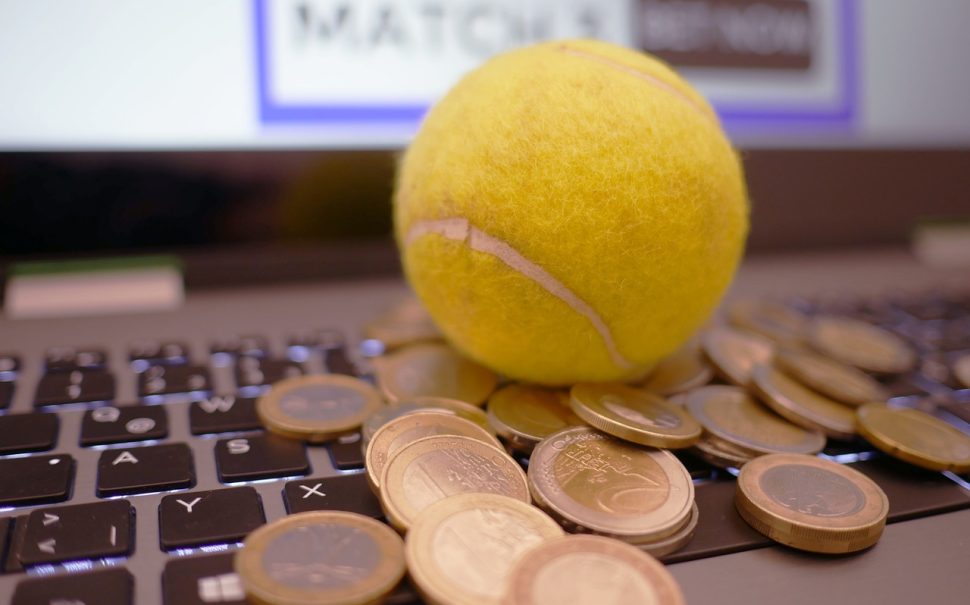 A tennis ball sitting on a pile of coins on a laptop