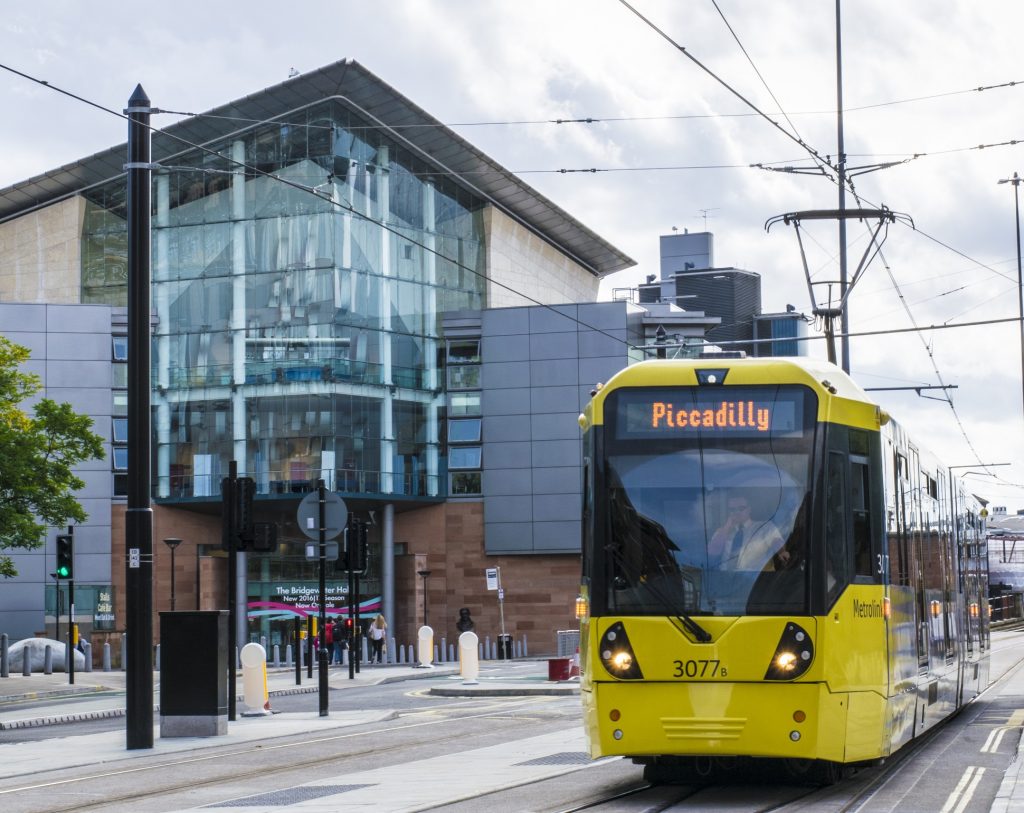 A photo of a Manchester Tram. The electronic sign on the front reads 'Piccadilly'.