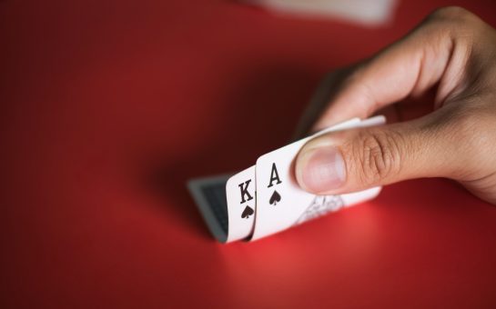 Blackjack cards in hands on red table.